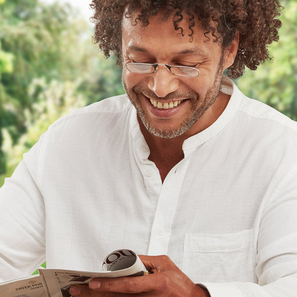 Man wearing Black ThinOptics Readers and reading a magazine